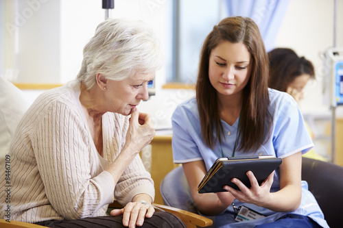 Woman Having Chemotherapy With Nurse Using Digital Tablet photo