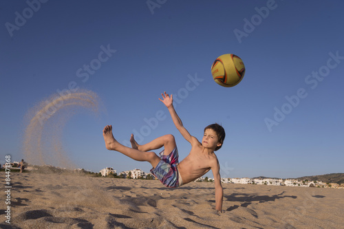 Boy playing soccer on the beach