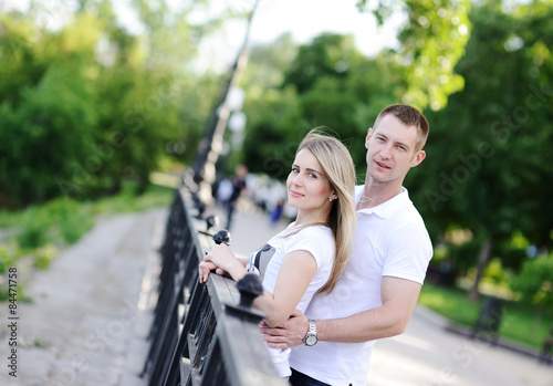 guy embraces the girl on a background of green trees (photograph