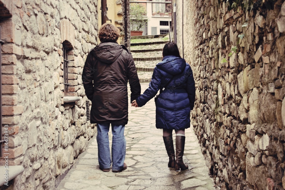 couple holding hands in the alley of the village Varzi - Lombardy - Italy