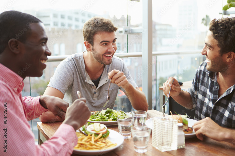 Three Male Friends Enjoying Lunch At Rooftop Restaurant