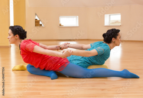 Two young women do yoga indoors