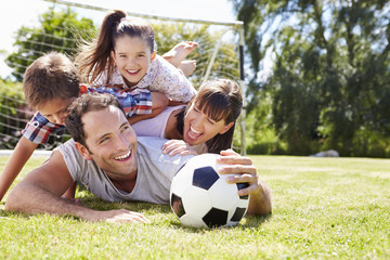 Family Playing Football In Garden Together