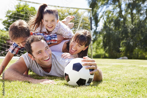 Fototapeta Naklejka Na Ścianę i Meble -  Family Playing Football In Garden Together