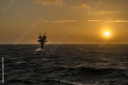 Caravel unmanned gas platform in rough seas silhouetted against