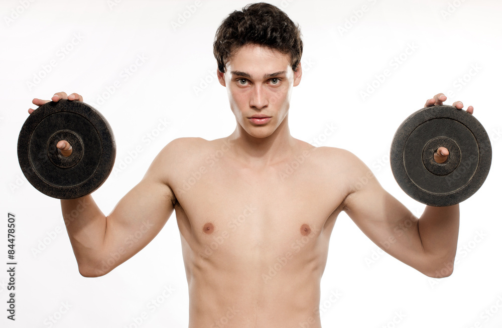 Skinny man training his bicep muscle. Beautiful teenager lifting two dumbbells.Anorexic young man training to become stronger Skinny man training his bicep muscle. Beautiful teenager lifting two dumbbells.Anorexic young man training to become stronger