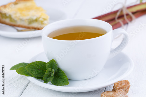 Mint tea with slice of rhubarb pie on wooden table.
