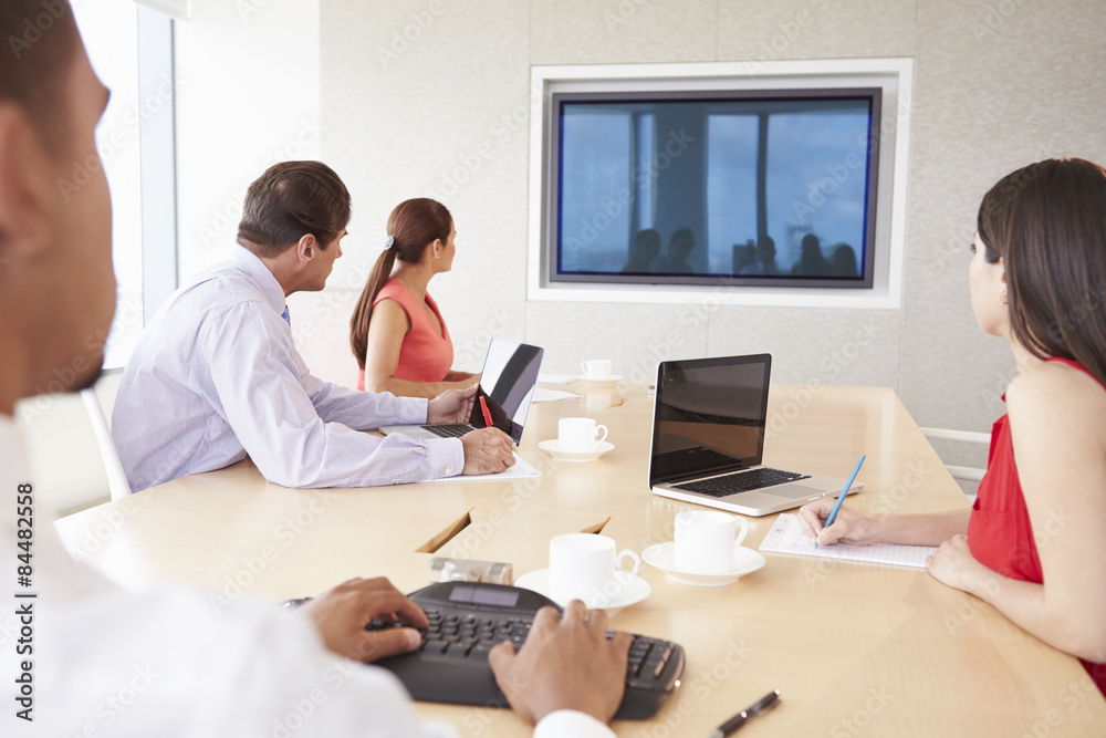 Four Businesspeople Having Video Conference In Boardroom Four Businesspeople Having Video Conference In Boardroom