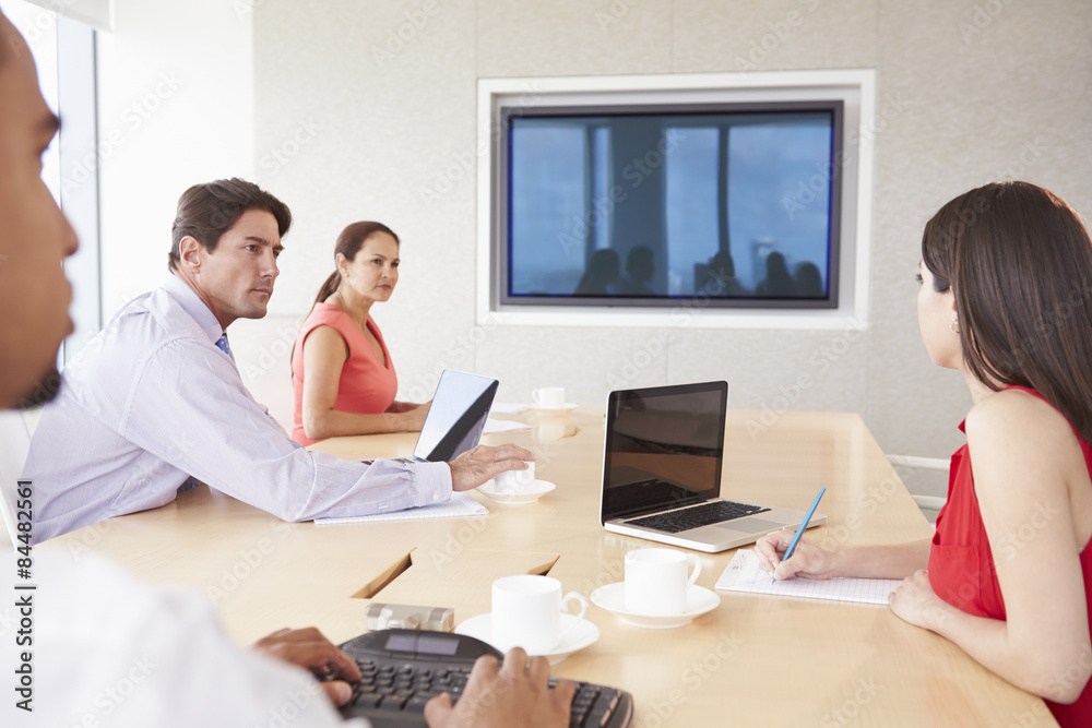 Four Businesspeople Having Video Conference In Boardroom Four Businesspeople Having Video Conference In Boardroom
