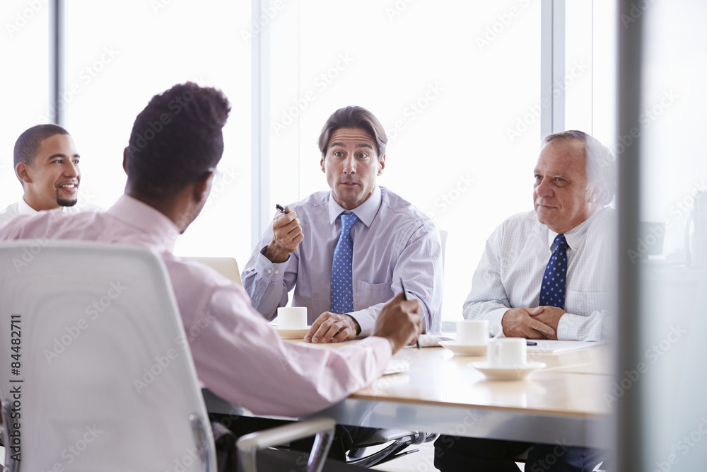 Obraz premium Four Businessmen Having Meeting Around Boardroom Table