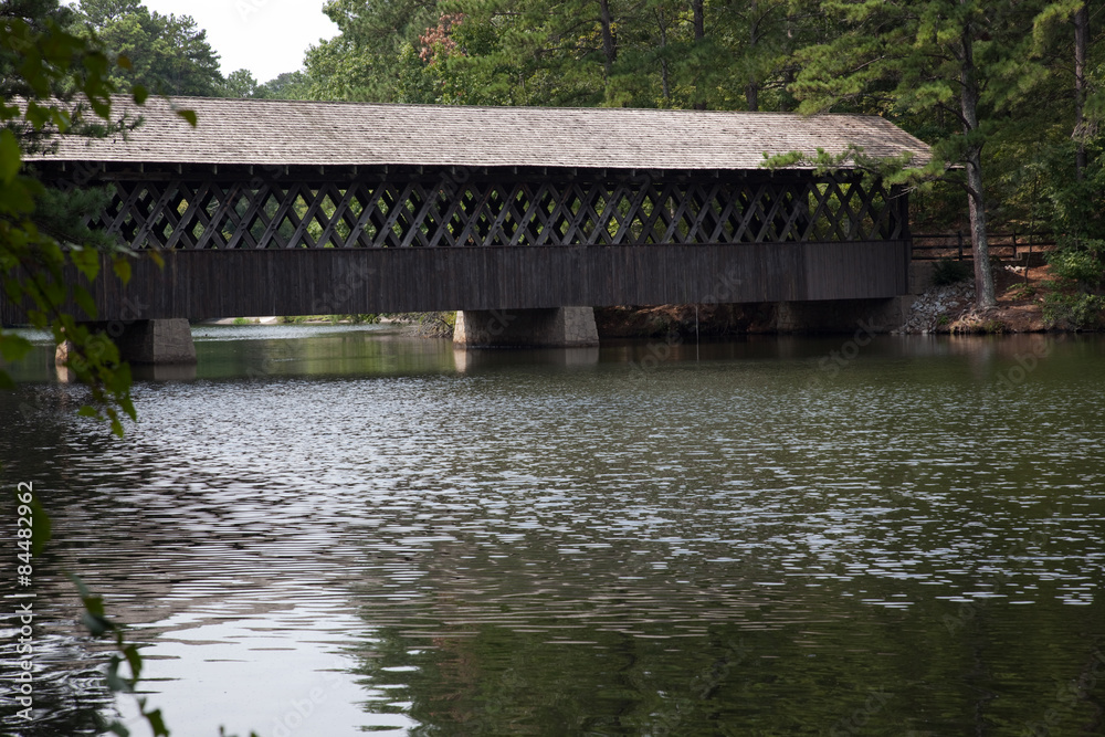 Wooden covered bridge over a still lake