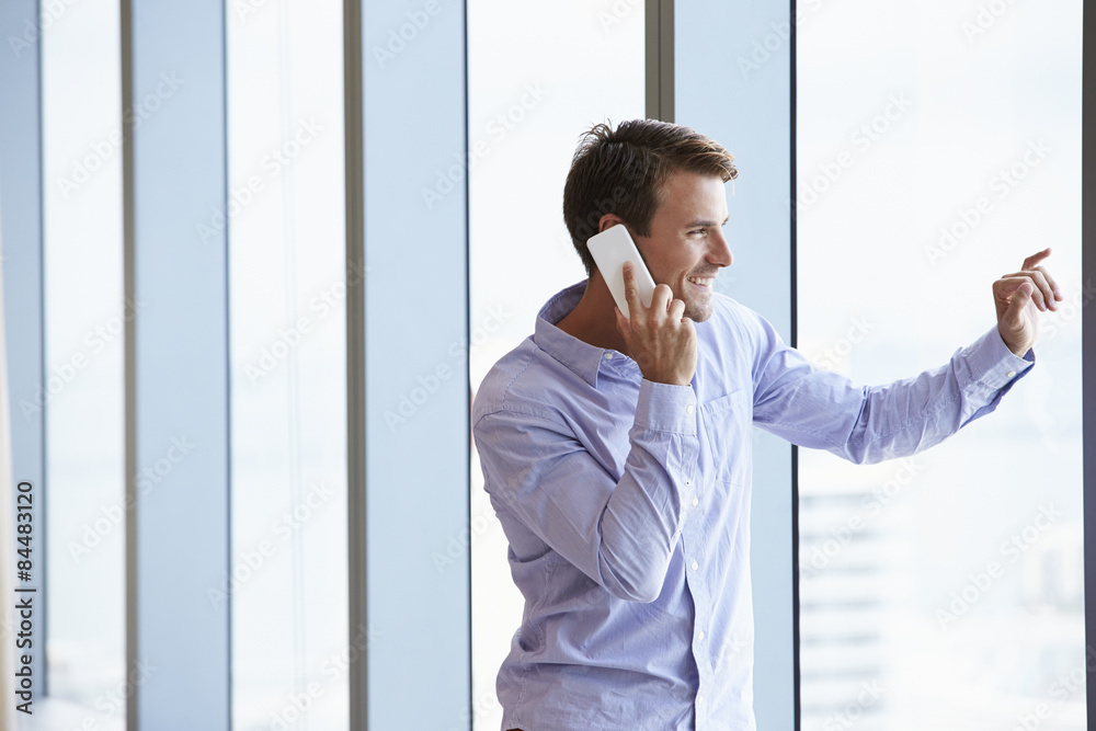 Casually Dressed Businessman Using Mobile Phone In Office Casually Dressed Businessman Using Mobile Phone In Office