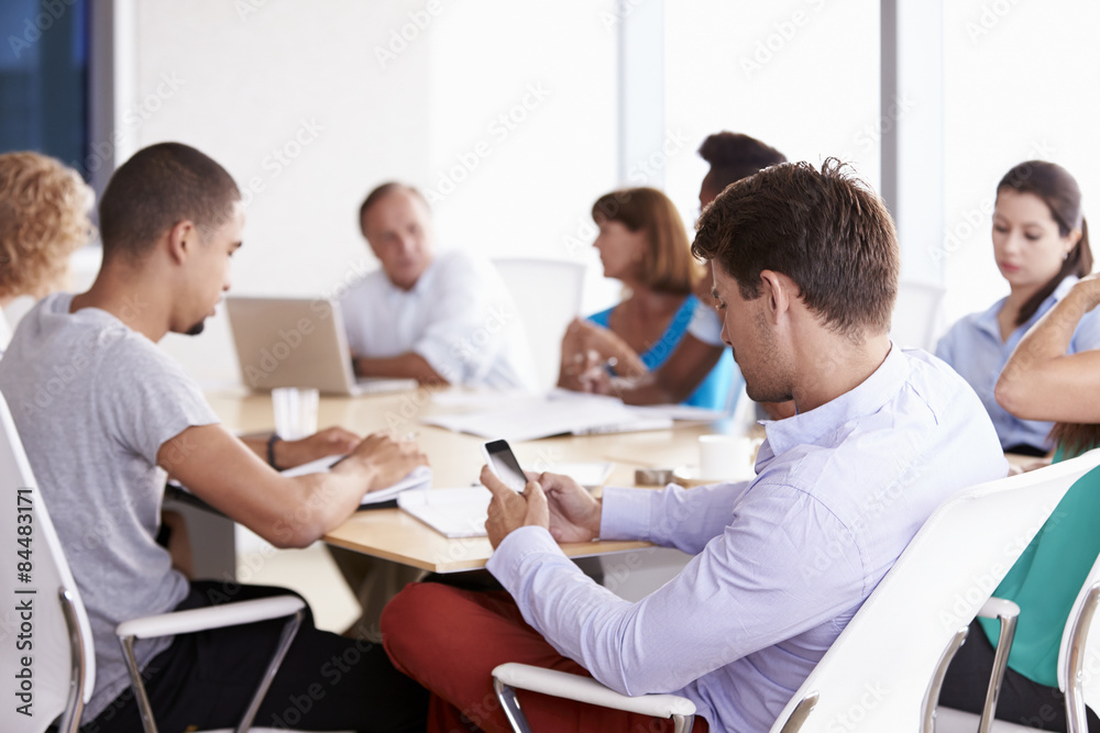 Businessman Using Mobile Phone In Boardroom Meeting Businessman Using Mobile Phone In Boardroom Meeting