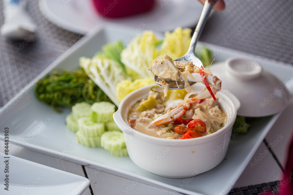 stew crab with coconut milk dip with fresh vegetables on white plates.