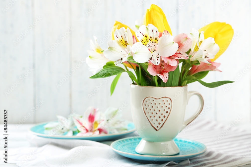 Beautiful flowers in cup, on wooden background Beautiful flowers in cup, on wooden background