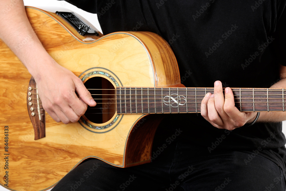 Fototapeta premium Young man playing on acoustic guitar close up