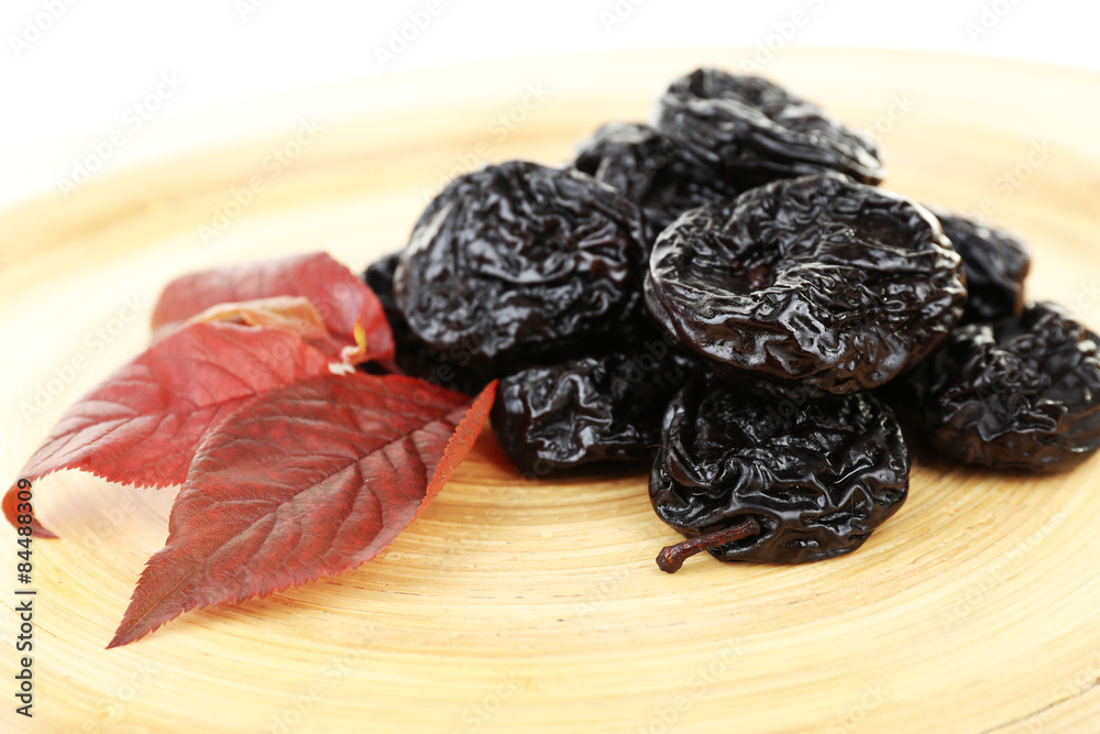 Pile of prunes with leaves on wooden background Pile of prunes with leaves on wooden background