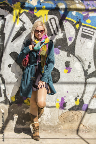 Young fashionable woman near the urban street wall.
