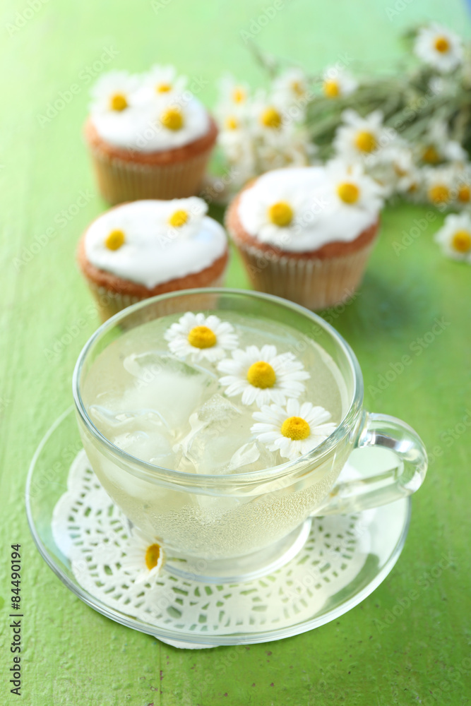 Cup of chamomile tea with chamomile flowers and tasty muffins on color wooden background Cup of chamomile tea with chamomile flowers and tasty muffins on color wooden background
