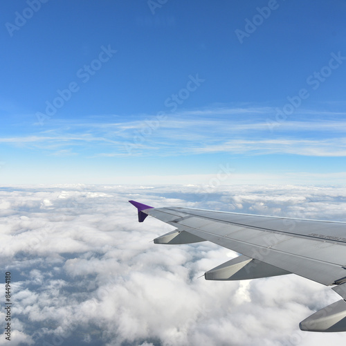 See through plane window with blue sky and clouds outside