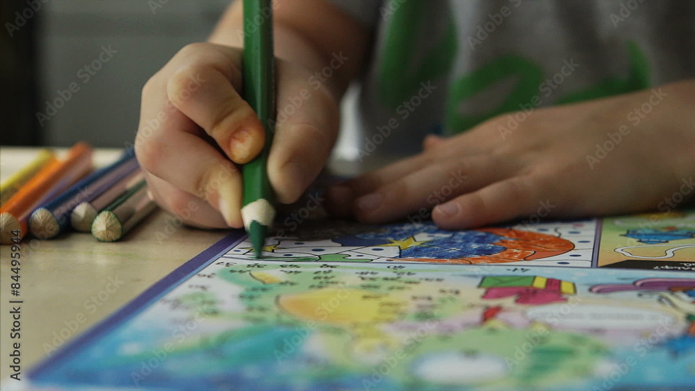 Child hands draws a green pencils on a paper
