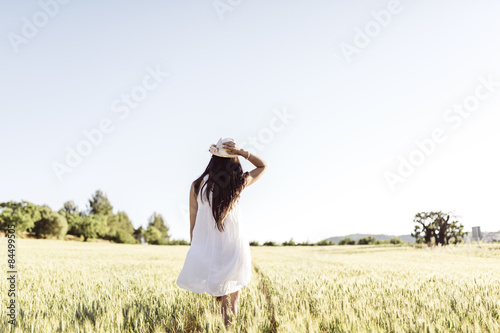 Happy young woman in a dress and a hat on the field