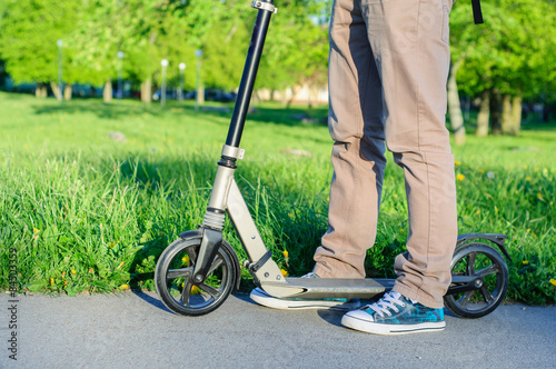 Young man in casual wear on kick scooter in park