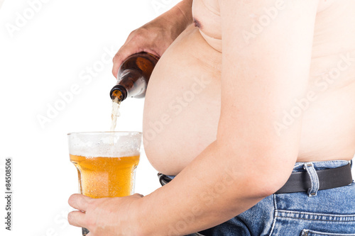 Obese man with big belly pouring a glass of refreshing beer