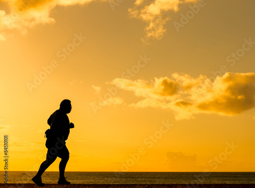 Silhouette fat man running at sunset