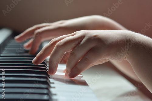 Детские руки на клавиатуре рояля при дневном освещении