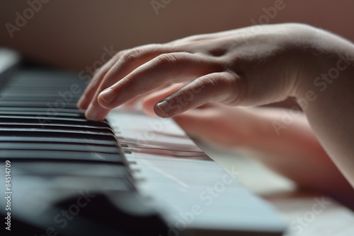 Детские руки на клавишах пианино при дневном свете