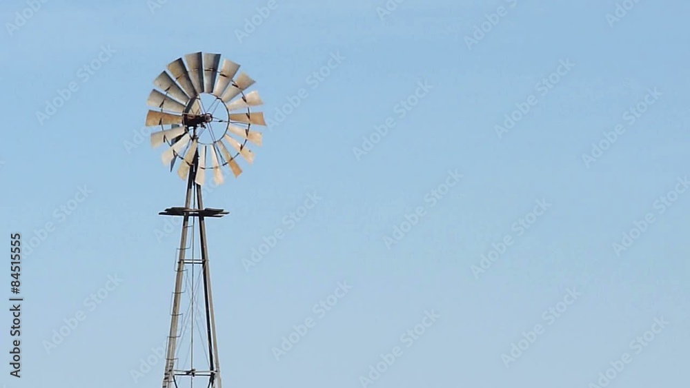 Close-up to a rotating windmill for pumping water over blue sky Close-up to a rotating windmill for pumping water over blue sky
