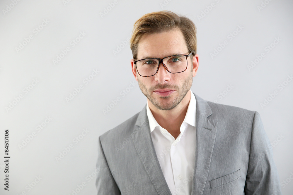 Businessman with eyeglasses standing on grey background, isolated