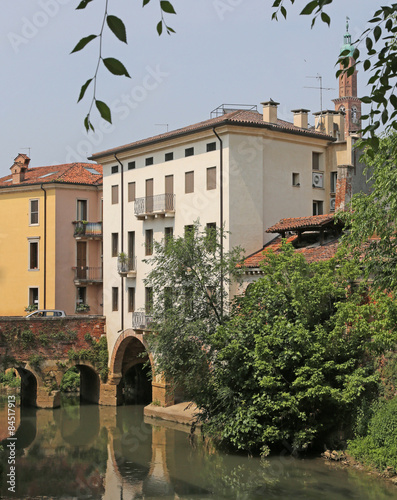 Ancient arched bridge over the River and houses in italy photo