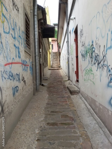Narrow street with grafitti on walls © pasicevo