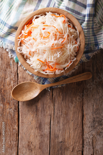 sauerkraut and carrots in a wooden plate. vertical top view 