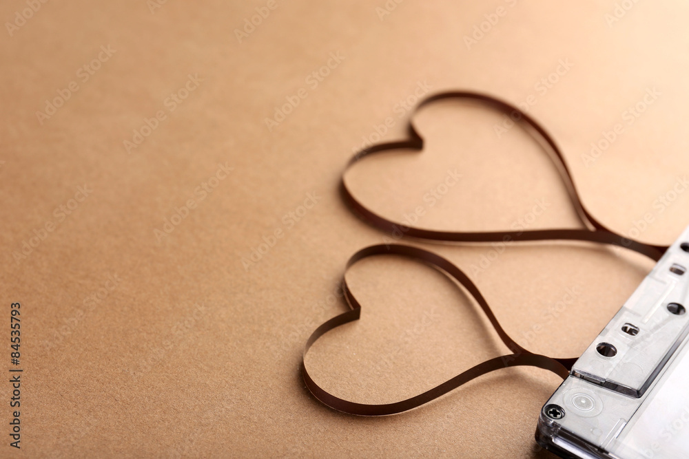 Audio cassette with magnetic tape in shape of hearts on brown background Audio cassette with magnetic tape in shape of hearts on brown background