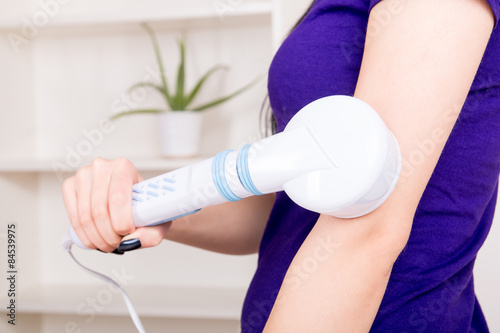 Woman massaging the body with infrared lamps massager photo