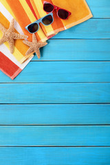 Beach background border scene with old blue wood deck decking sunglasses and sunbathing towel summer holiday vacation photo vertical