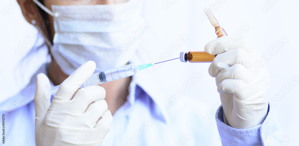 Doctora cargando una medicación en la geringa. Doctora cargando una medicación en la geringa.