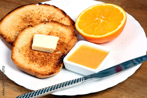 european served breakfast: toasts with jam, butter and orange
