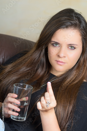 pretty brunette lady showing a pill between her fingers and