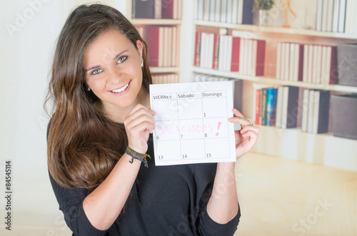 portrait of pretty brunette girl holding up a calendar