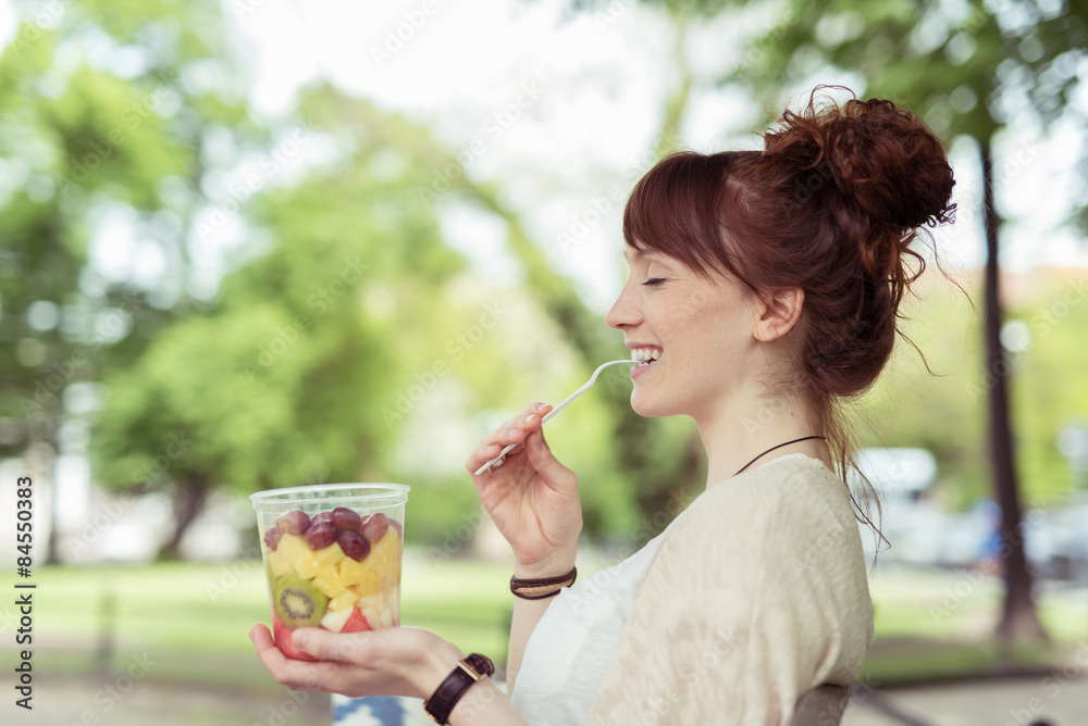 junge frau genießt einen frische obstsalat junge frau genießt einen frische obstsalat