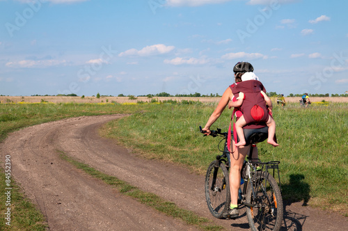 Young mother with her baby mountain bike ride on dirt road.