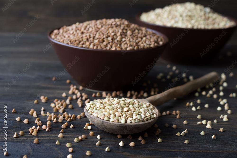 Green and brown buckwheat in ceramic bowls on a wooden surface Green and brown buckwheat in ceramic bowls on a wooden surface