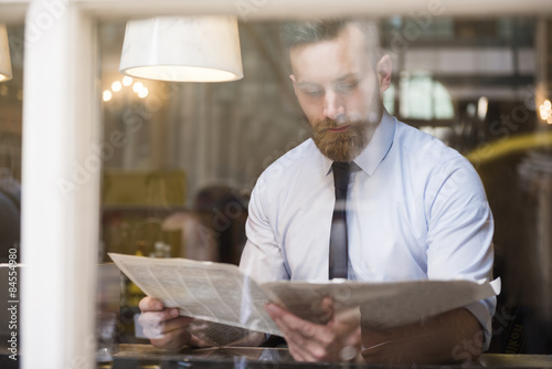 Foto Young businessman reading newspaper