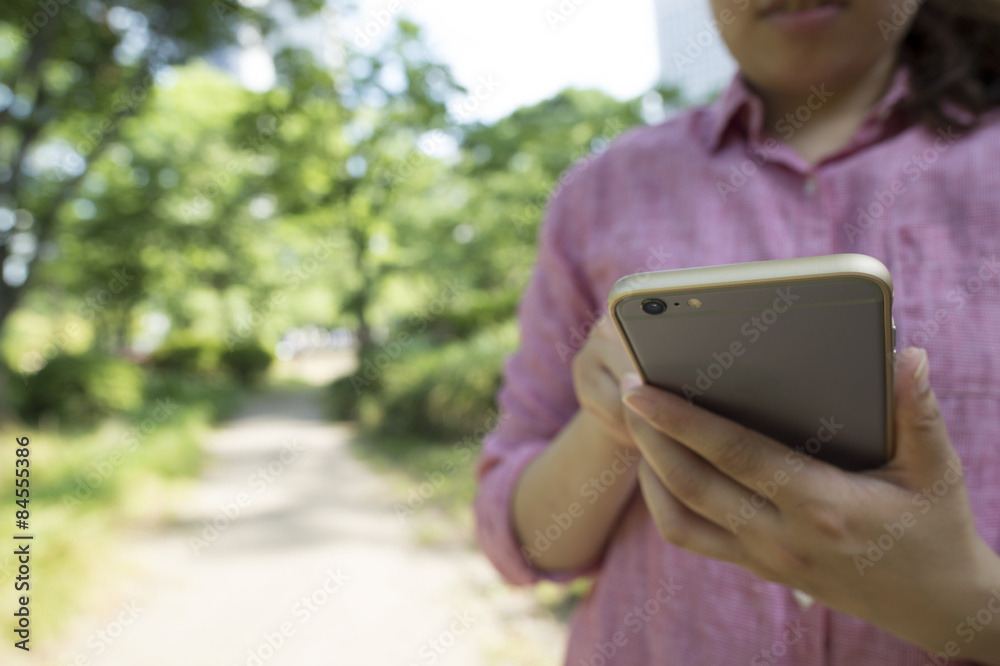 Young woman looking at a smart phone in the park Young woman looking at a smart phone in the park