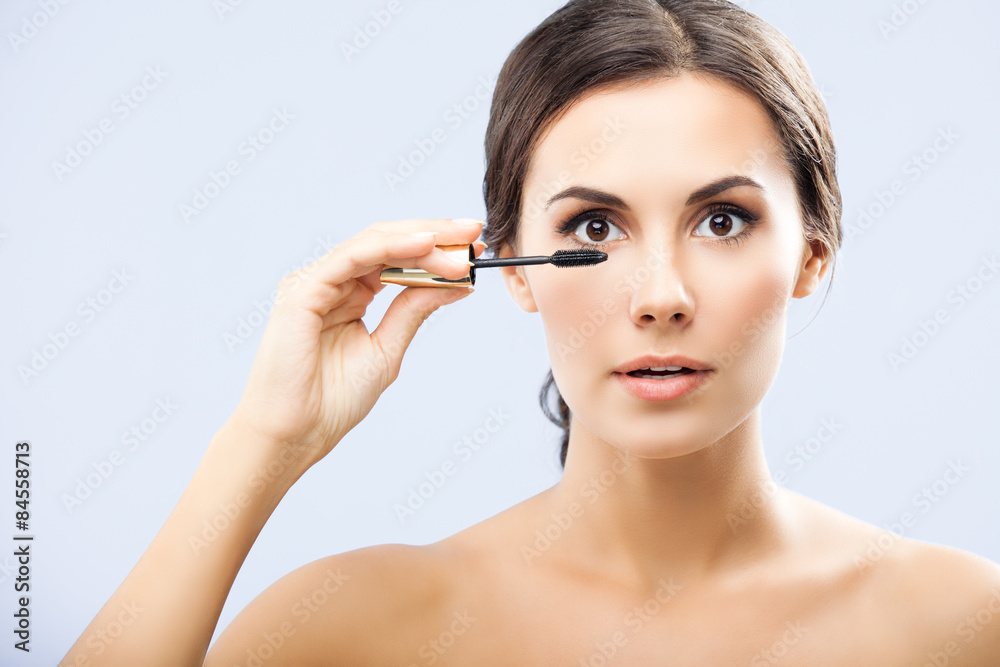 Woman with cosmetics brush, on grey