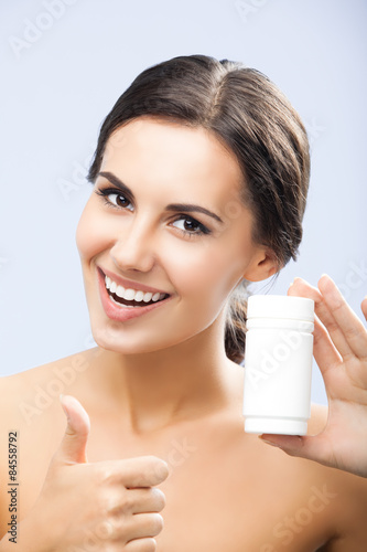 Smiling woman showing medical drug, over grey